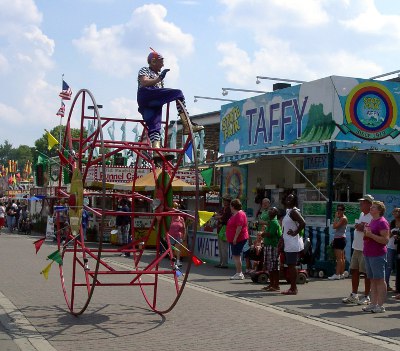 [Costumed man atop a giant metal-framed rolling device waving to those watching the parade.]